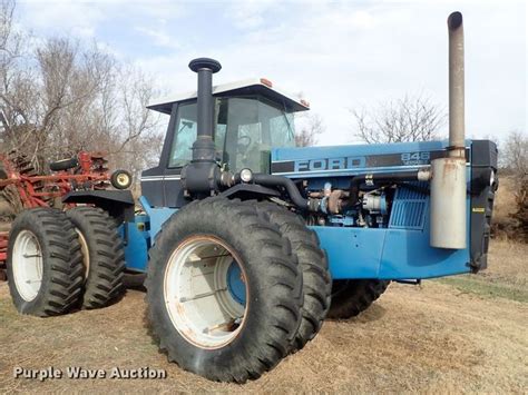 A Blue Tractor Parked On Top Of A Dry Grass Field