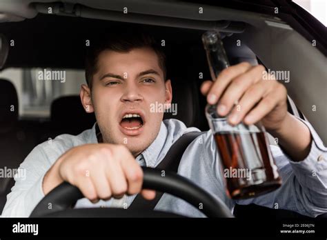 Drunk Aggressive Man Shouting While Driving Car And Holding Bottle Of