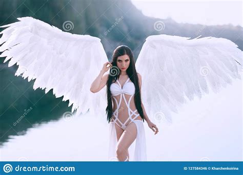 A Heavenly Angel In A Fabulous Dress With White Wings Walks Against