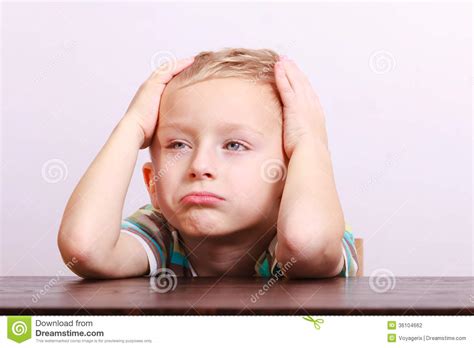Portrait Of Sad Emotional Blond Boy Child Kid At The Table Stock Photo