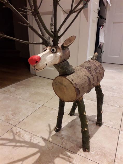 A Deer Made Out Of Tree Trunks On The Floor In Front Of A Door With Its