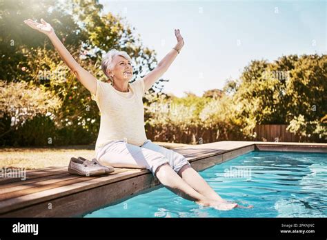 Hooray Summers here. a joyful senior woman dipping her feet in a