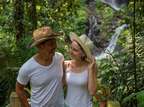 Multicultural Couple Enjoying Waterfall Scenery In Tropical Rainforest Young Mixed Race Couple