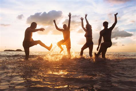 group of happy friends having fun together on the beach at sunset 