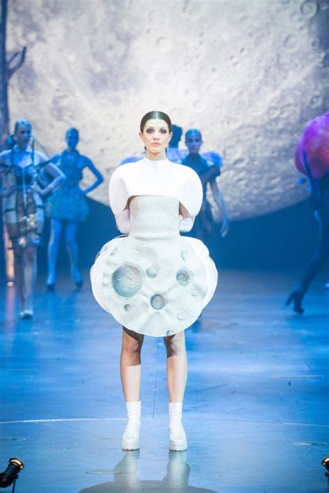 A Woman Is Walking Down The Runway Wearing A White Dress With Holes On