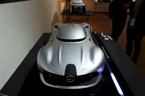 A Mercedes Sports Car Is On Display In A Showroom With People Looking At It