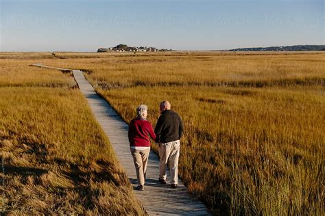Senior Couple Walking Down Boardwalk Del Colaborador De Stocksy