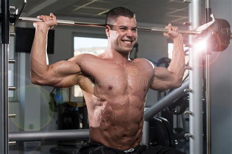 Male Bodybuilder Doing Heavy Weight Exercise For Shoulders Stock Photo