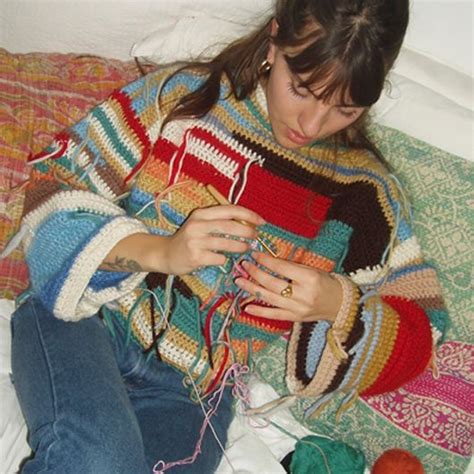 A Woman Sitting On Top Of A Bed Holding A Ball Of Yarn