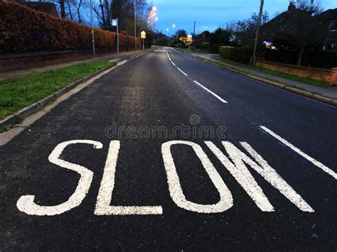 Painted Slow Warning Sign On Winding Country Road In England Stock