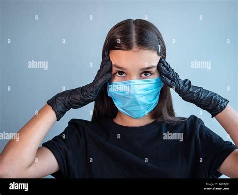 A Female Teenage Girl In A Blue Protective Medical Face Mask Touching