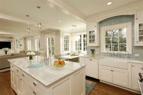 A Large Kitchen With White Cabinets And Marble Counter Tops