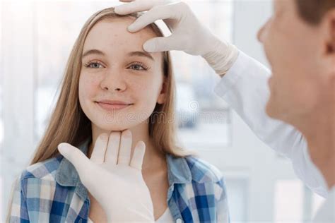 Careful Dermatologist Examining Patient Face At Work Stock Image