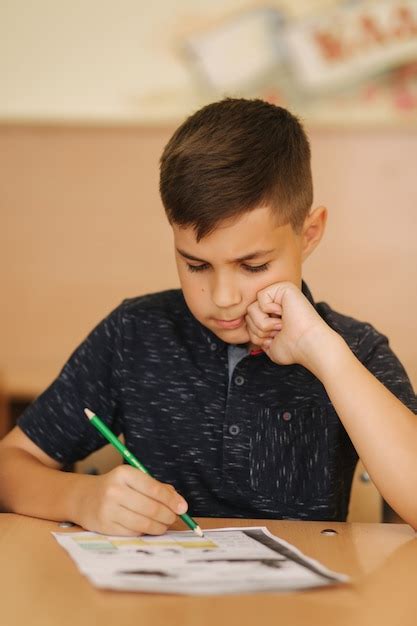 Écolier Concentré Assis Au Bureau Et écrit Dans Un Cahier Dexercices