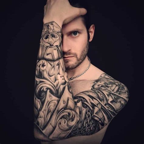 A Man With Tattoos On His Arm And Shoulder Is Holding His Hand Up To