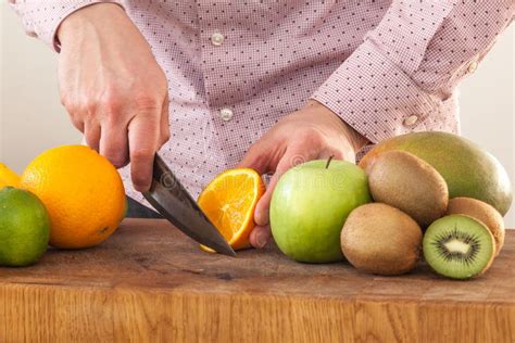 Man Cuts Fruit On A Wood Cutting Board Stock Photo Image Of Kiwi