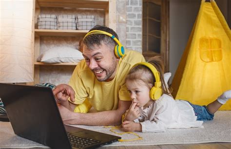 Un Padre Feliz Con Su Pequeña Hija Está Tirado En El Suelo Con Auriculares Amarillos Riendo