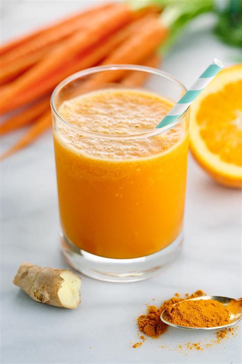 A Glass Filled With Orange Juice Next To Carrots