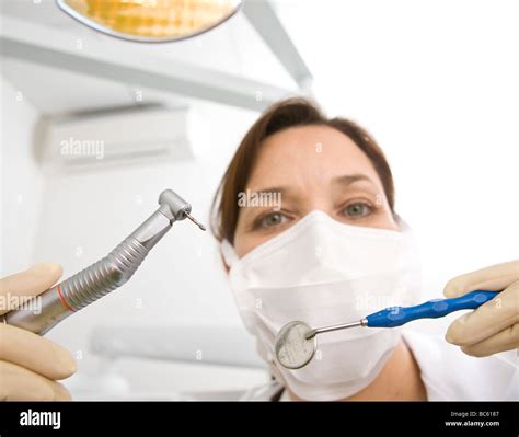 Portrait Of Female Dentist Holding Dental Drill And Angled Mirror Stock