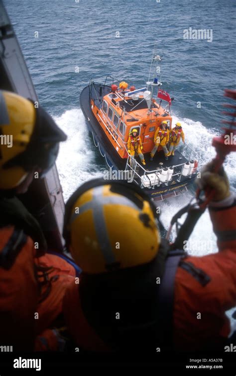 Coastguard Search And Rescue Helicopter Flies Over Rnli Lifeboat Stock
