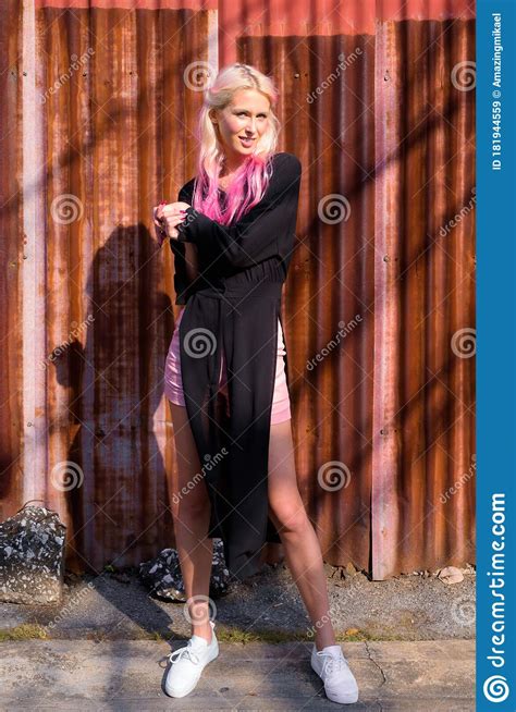 Full Body Shot Of Young Beautiful Blonde Woman Against Rusty Iron Wall