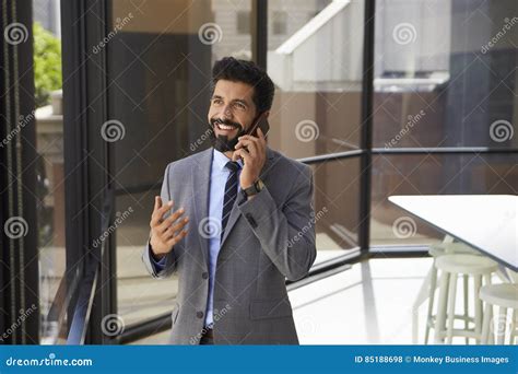 Усмехаясь середина постарела испанский бизнесмен на телефоне в офисе