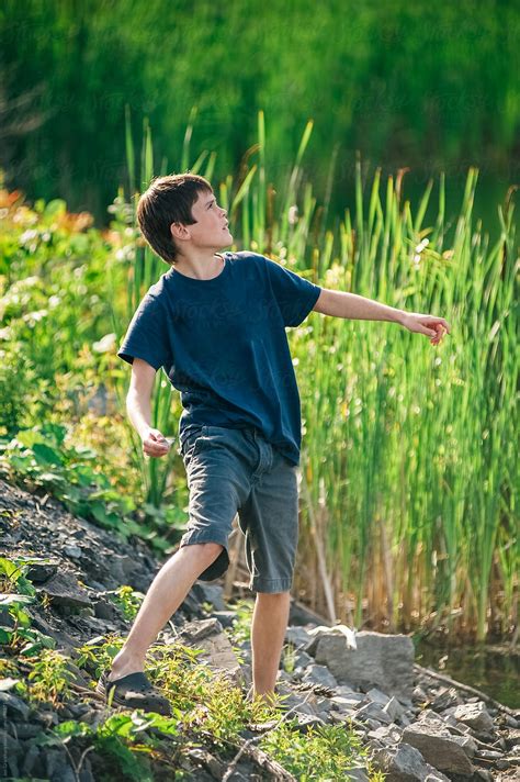 Boy Throwing Rocks At The Side Of The Road By Stocksy Contributor
