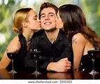 Two Young Attractive Sweet Women Kissing Man With Redwine Glasses At ...