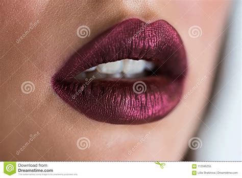 closeup of beautiful woman lips with purple lipstick open mouth with white teeth cosmetics