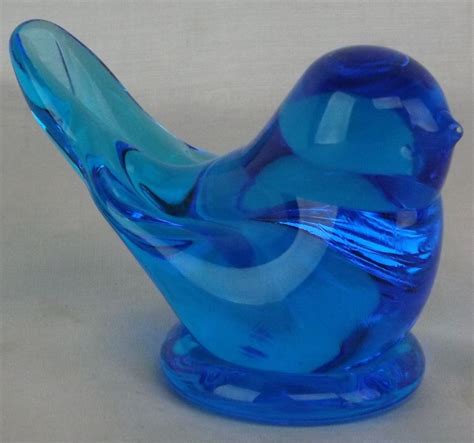 A Blue Glass Bird Sitting On Top Of A Table