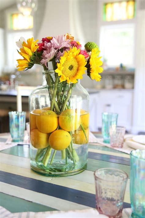 A Vase Filled With Lemons And Flowers Sitting On Top Of A Table Next To