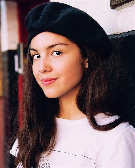 A Young Woman Wearing A Black Beret Standing Next To A Wall