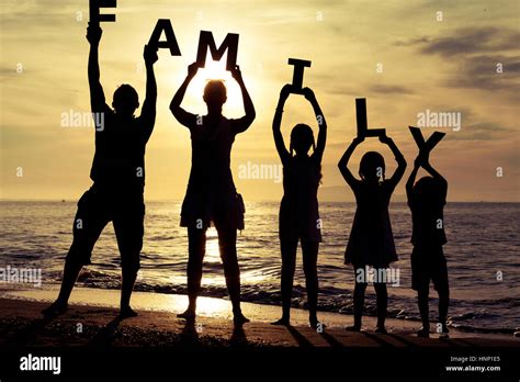Happy family standing on the beach at the sunset time. They keep the