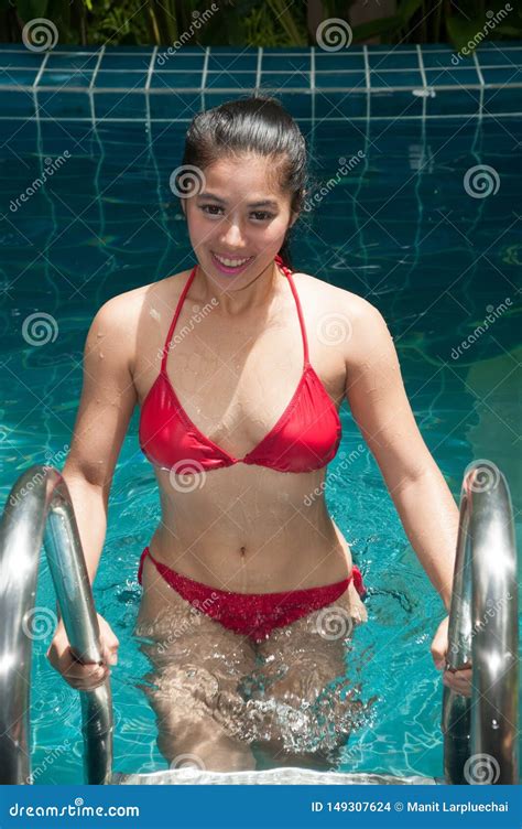 Pretty Asian Woman Wearing Red Bikini Swim And Standing At Stair At Swimming Pool Stock Photo