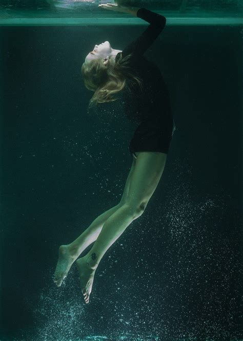 A Woman In Black Swimsuit Diving Under Water