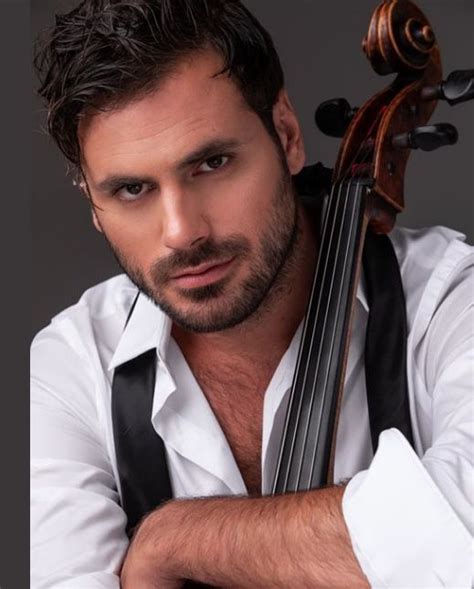 A Man Holding A Violin In His Right Hand And Looking At The Camera