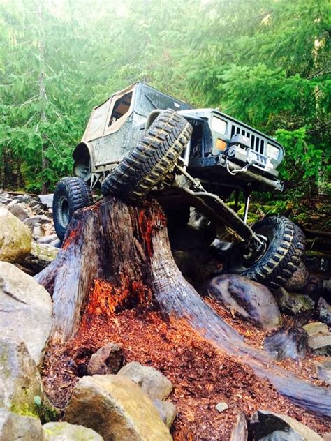 An Off Road Vehicle Is On Top Of A Tree Stump In The Middle Of Some Rocks