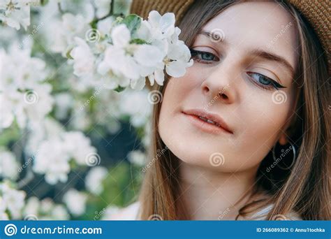 Beautiful Young Girl In White Dress And Hat In Blooming Apple Orchard