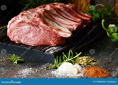 Fresh Raw Pork Loin On The Bone On A Wooden Board With Herbs Spices