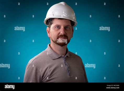 Construction Worker With Beard And White Safety Helmet Looking Into The