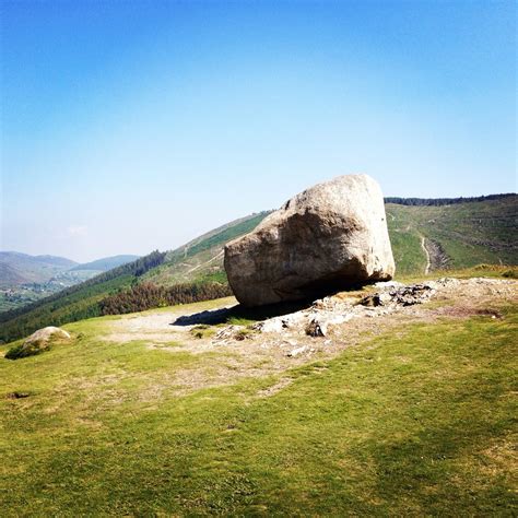 A Large Rock Sitting On Top Of A Lush Green Hillside