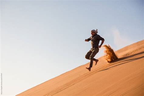 Man Jumping From A Sand Dune In The Desert By Stocksy Contributor