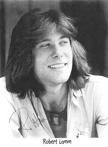 A Black And White Photo Of A Man With Long Hair Smiling At The Camera
