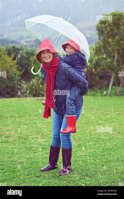 playful in the rain cropped portrait of a mother carrying her son on her back outside in the