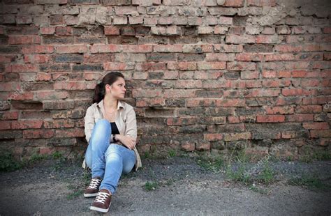 Sad Young Girl Sitting Against A Brick Wall — Stock Photo © Drtrig