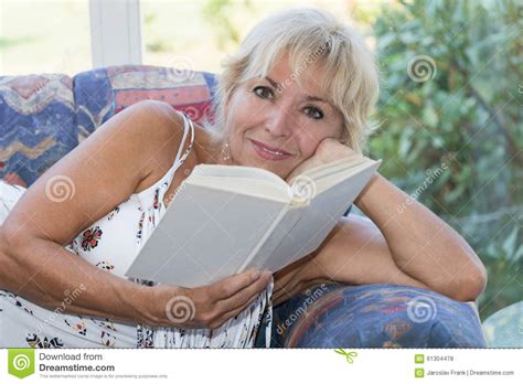 La Mujer Rubia Madura Atractiva Está Leyendo Un Libro Foto De Archivo