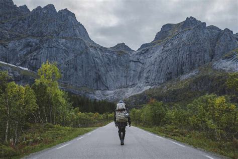 Norway Lofoten Islands Backpacker Walking Down Road In Mountain