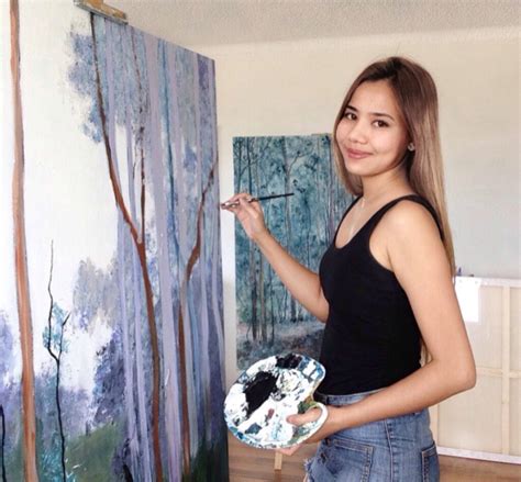 A Woman Holding A Paintbrush And Palette In Front Of A Painting