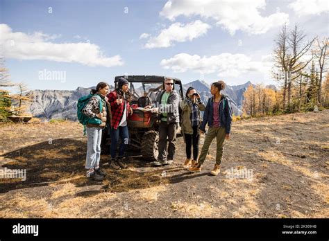 Guide with trail map helping hikers at UTV on majestic autumn mountain