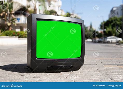 Old Tv Set With A Green Screen On The City Street With Cars Stock Photo